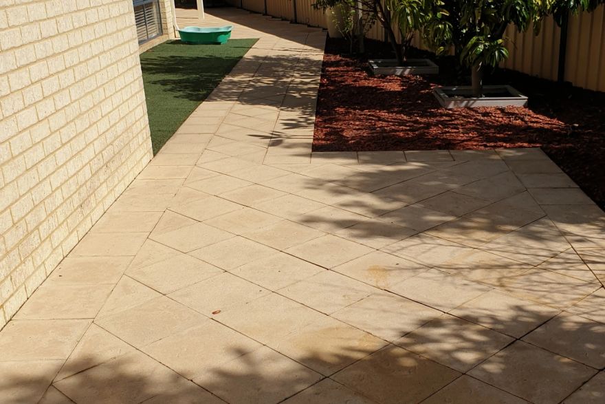 Before and after cleaning on sandstone pavers · Side of house: after