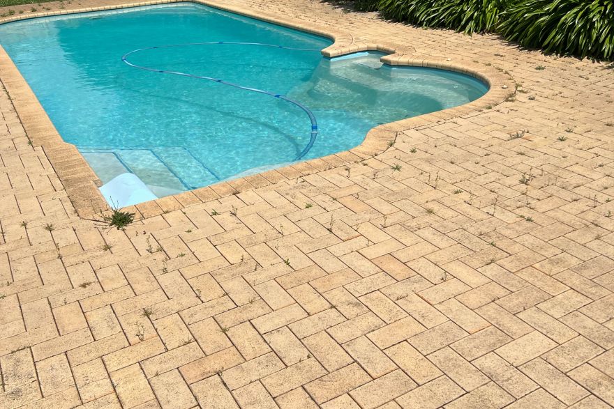 Before and after cleaning on brick pavers · Poolside: before
