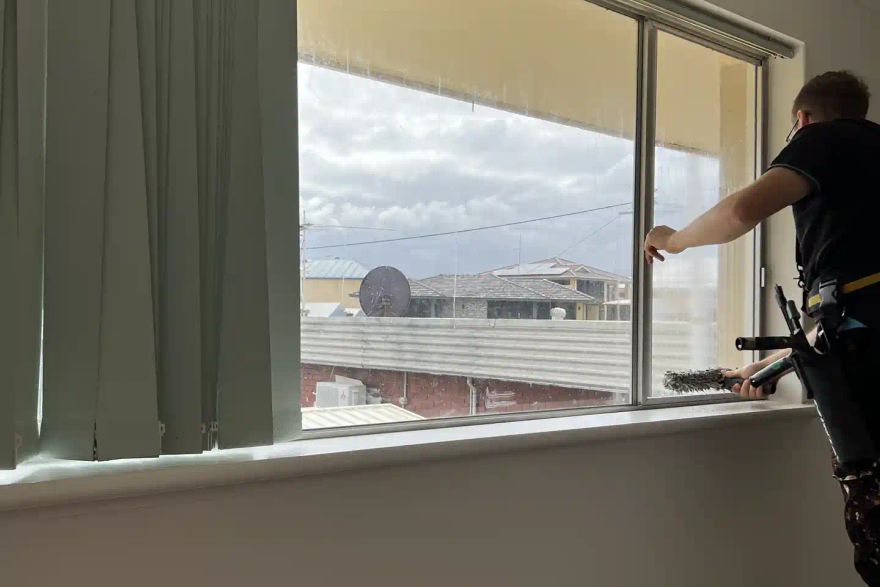 Michael washing a window inside a building.